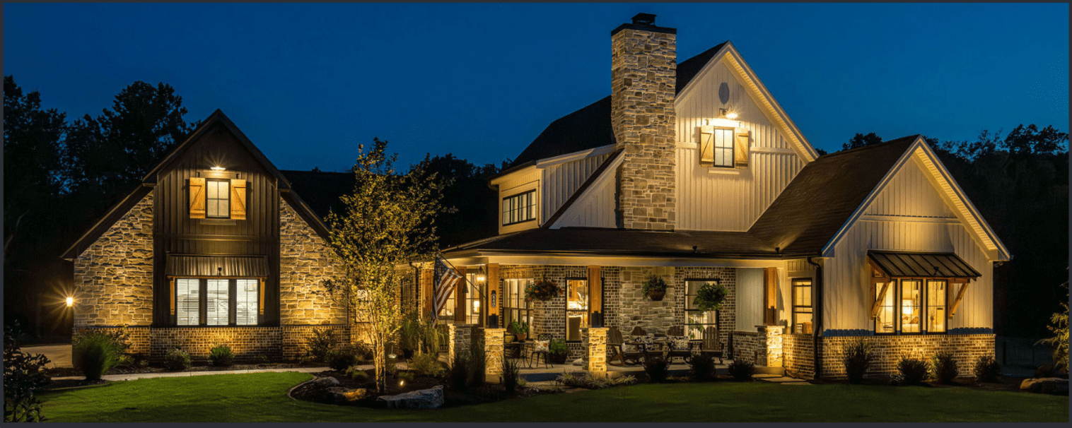 A cozy, warmly lit house at night with stone exterior and a lit porch.