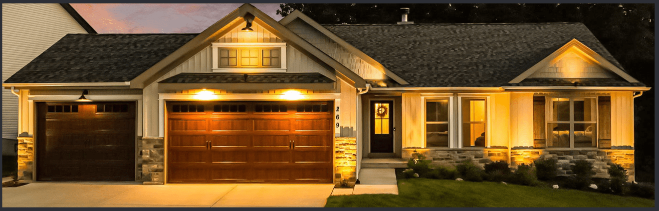 Well-lit modern house exterior at night with garage and front door.