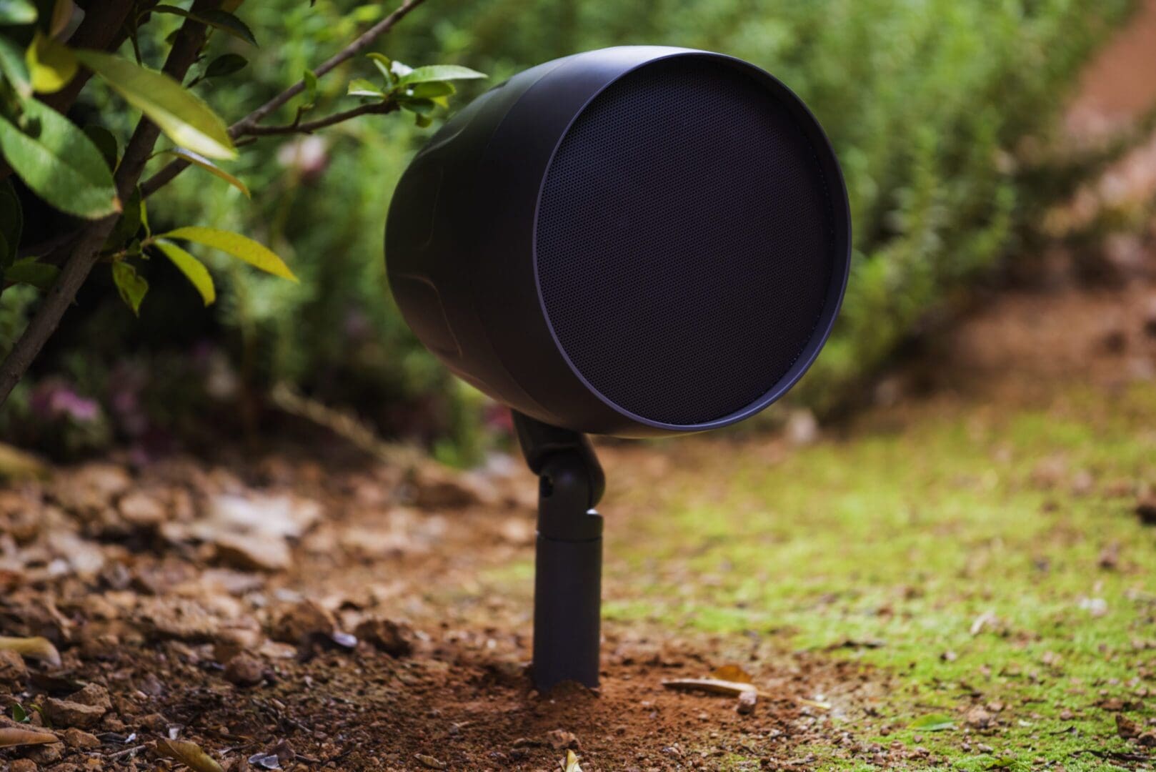 Black outdoor speaker mounted on a spike in the ground.